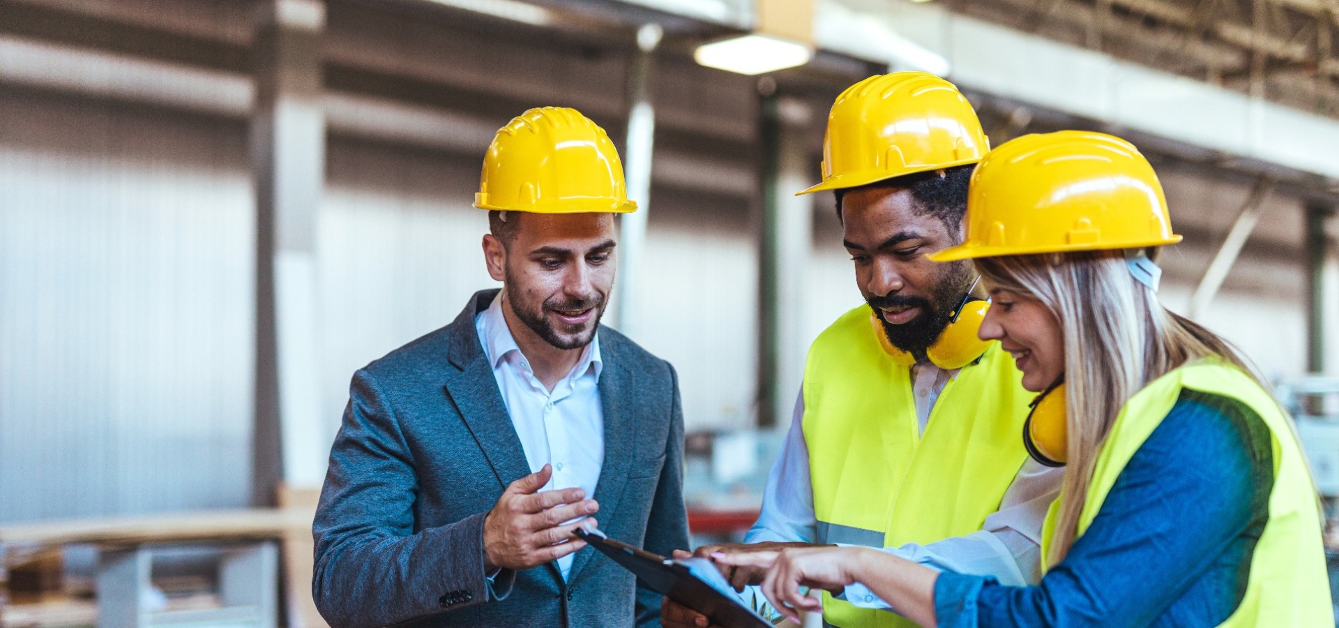Ingenieure bei der Zusammenarbeit in einer Fabrik mit Sicherheitshelmen und Warnwesten