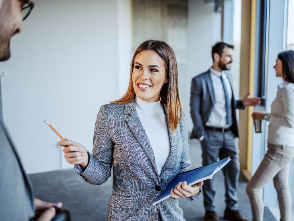 Lächelnde attraktive weibliche Vorgesetzte, die mit ihrem Mitarbeiter über neue Ideen für ein zu erneuerndes Gebäude spricht. Gebäude im Bauprozess innen.